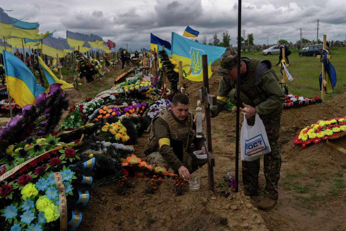 Two national guard visit the grave of a late soldier in Kharkiv cemetery, eastern Ukraine, Sunday, May 22, 2022.
