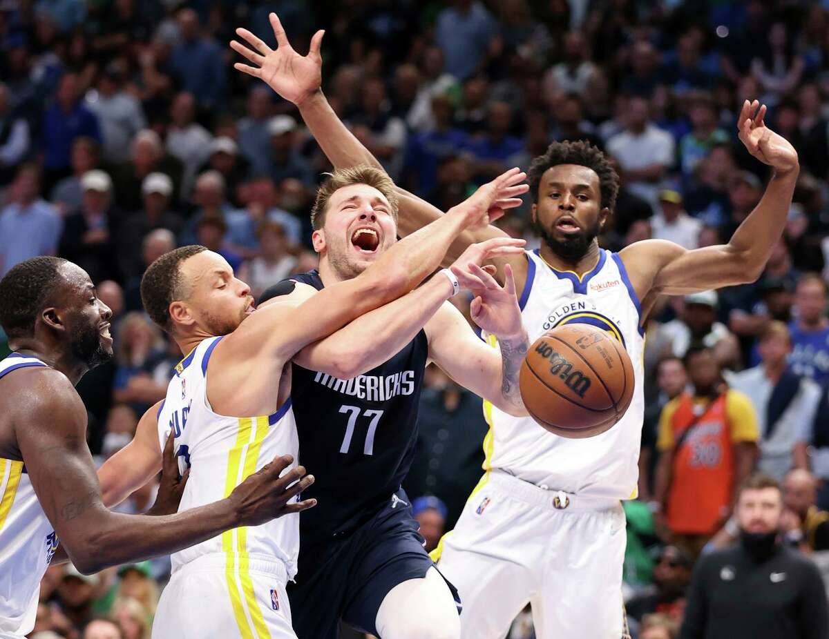 Dallas Mavericks’ Luka Doncic is fouled by Stephen Curry as Draymond Green and Andrew Wiggins watch in 4th quarter during Warriors’ 109-100 win in Game 3 of NBA Western Conference Finals at American Airlines Center in Dallas, Texas, on Sunday, May 22, 2022.