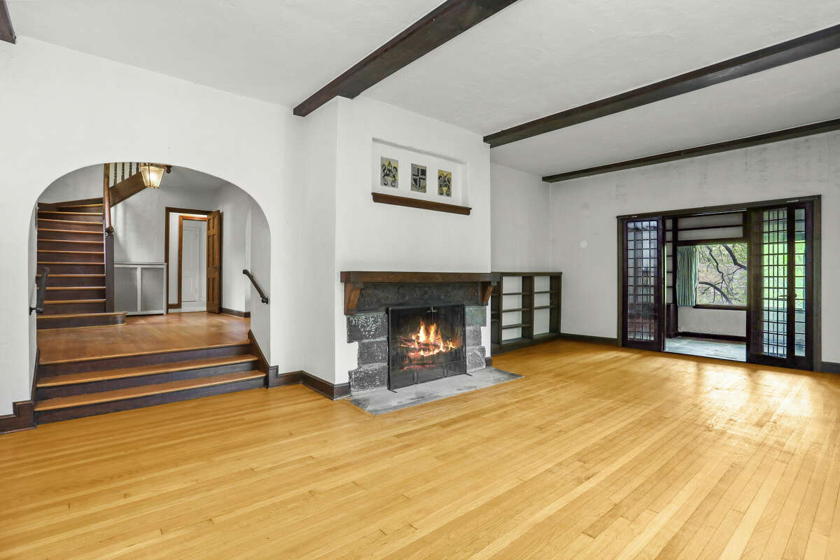 The expansive step-down living room at 107 Orchard Drive has great character, with hardwood floors, an archway entrance, beamed ceiling, French doors and wood-burning fireplace.