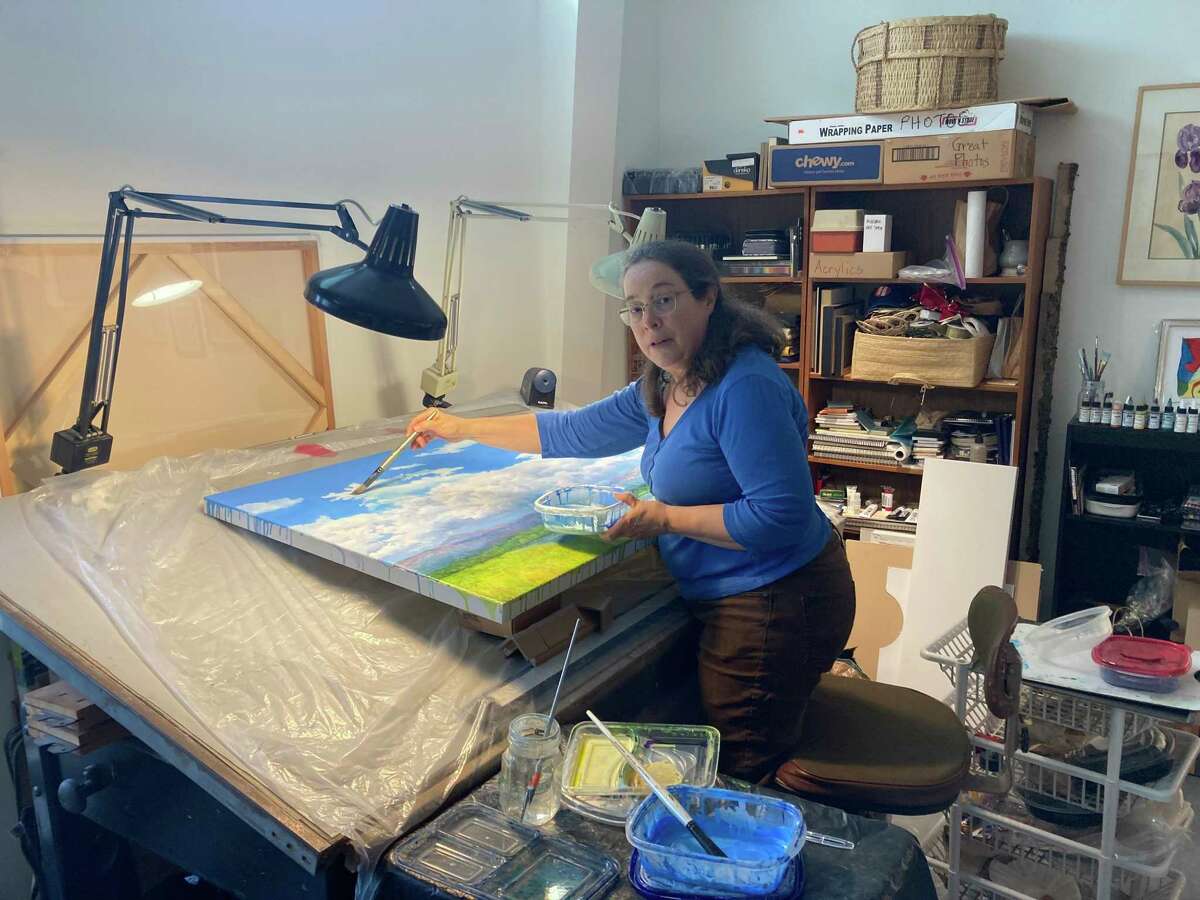 Artist Lucy Riggs in her studio at Art Square Studios on Almeda. Her 30 inch by 40 inchpainting is titled “Taken to Ten Mile.”