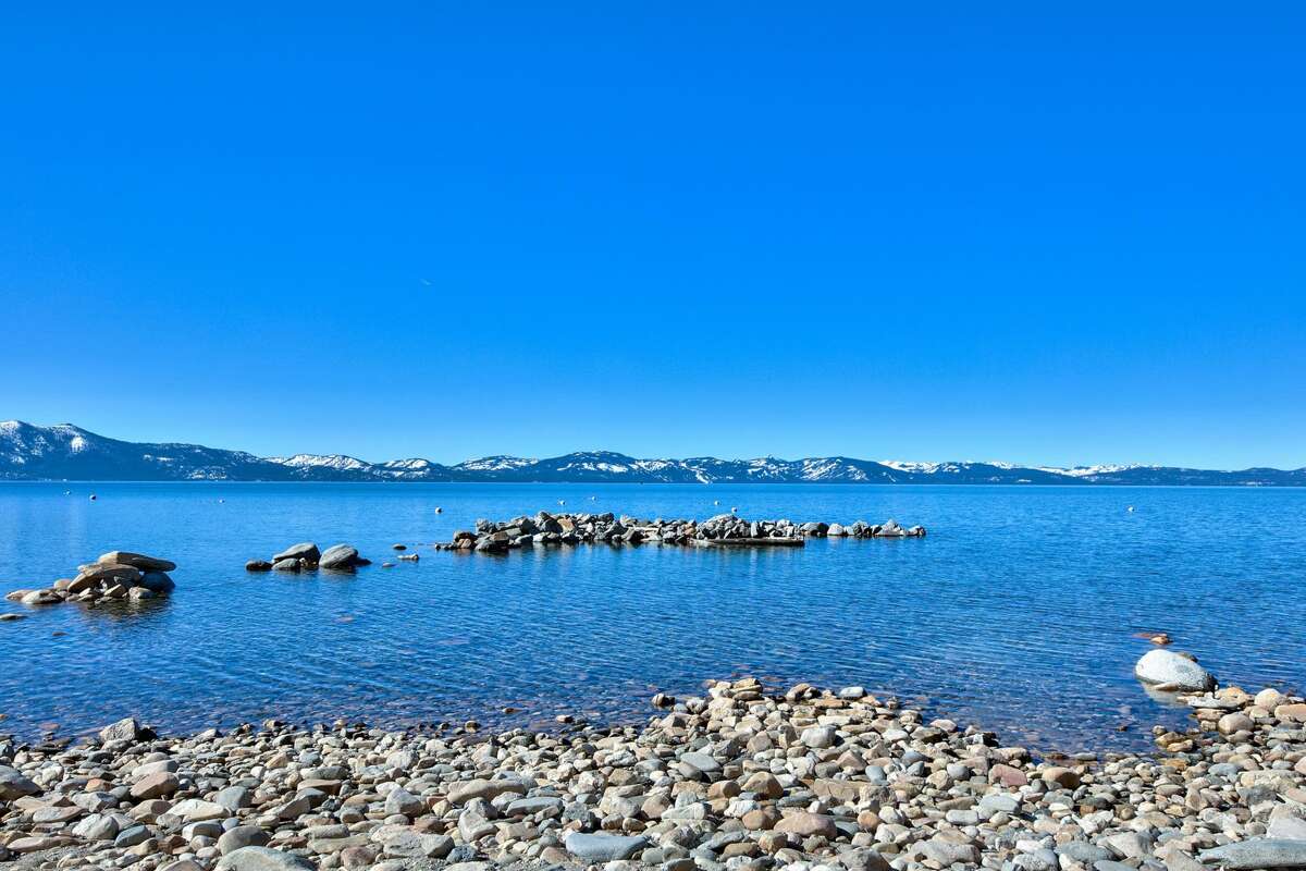 From the beach, the crystal blue of Lake Tahoe gives the mountains over there an azure glow. 
