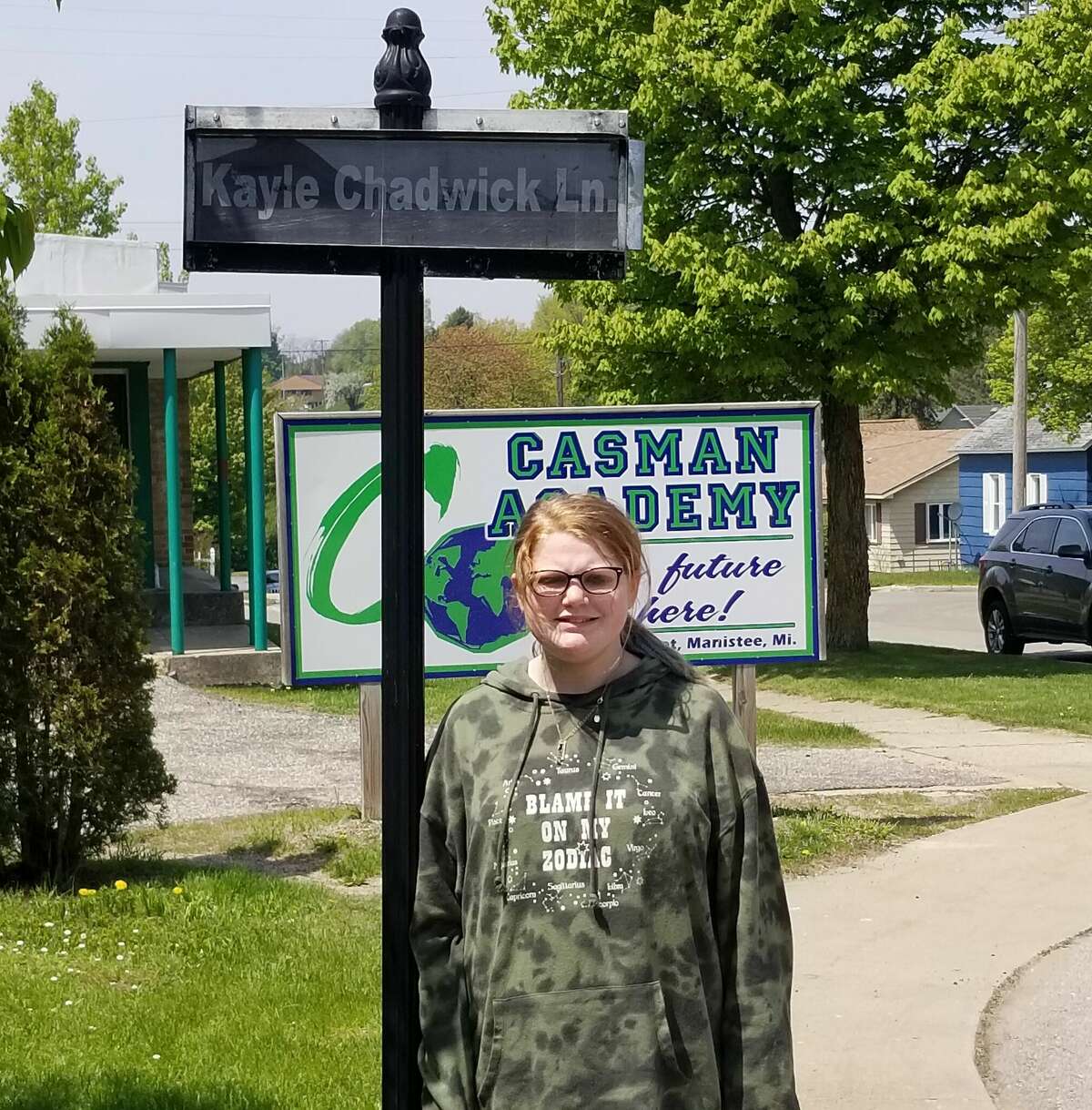 Kayle Chadwick, the CASMAN Academy Student of the Month, poses next to the sign that names the school driveway in her honor.