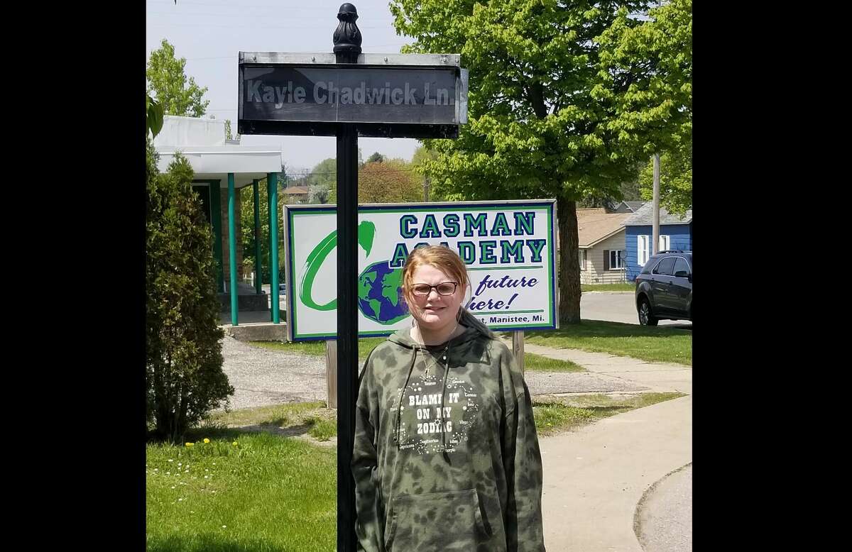 Kayle Chadwick, the CASMAN Academy Student of the Month, poses next to the sign that names the school driveway in her honor.