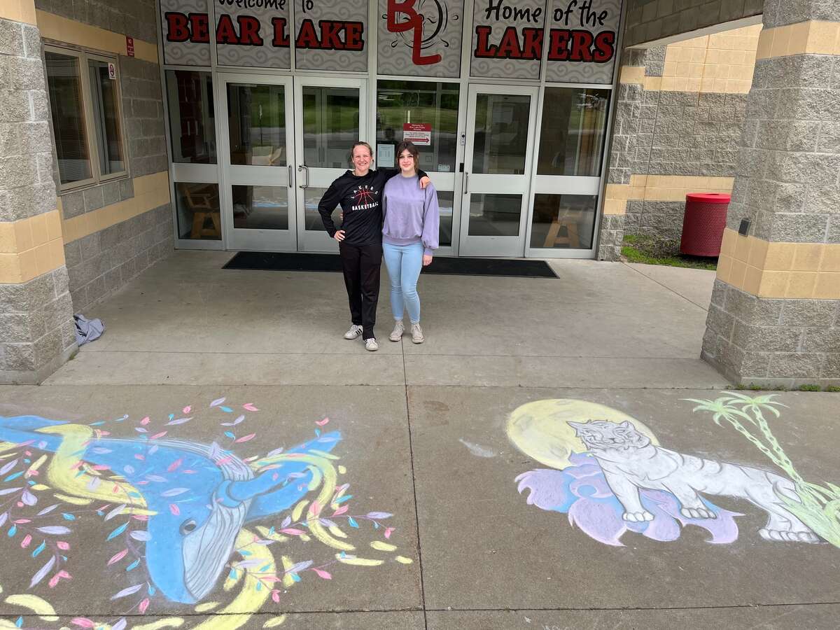 Bear Lake High School students Taylor Merrill and Victoria Hall pose for a photo next to the art they created as part of the second annual Endangered Species Chalk Art Event.