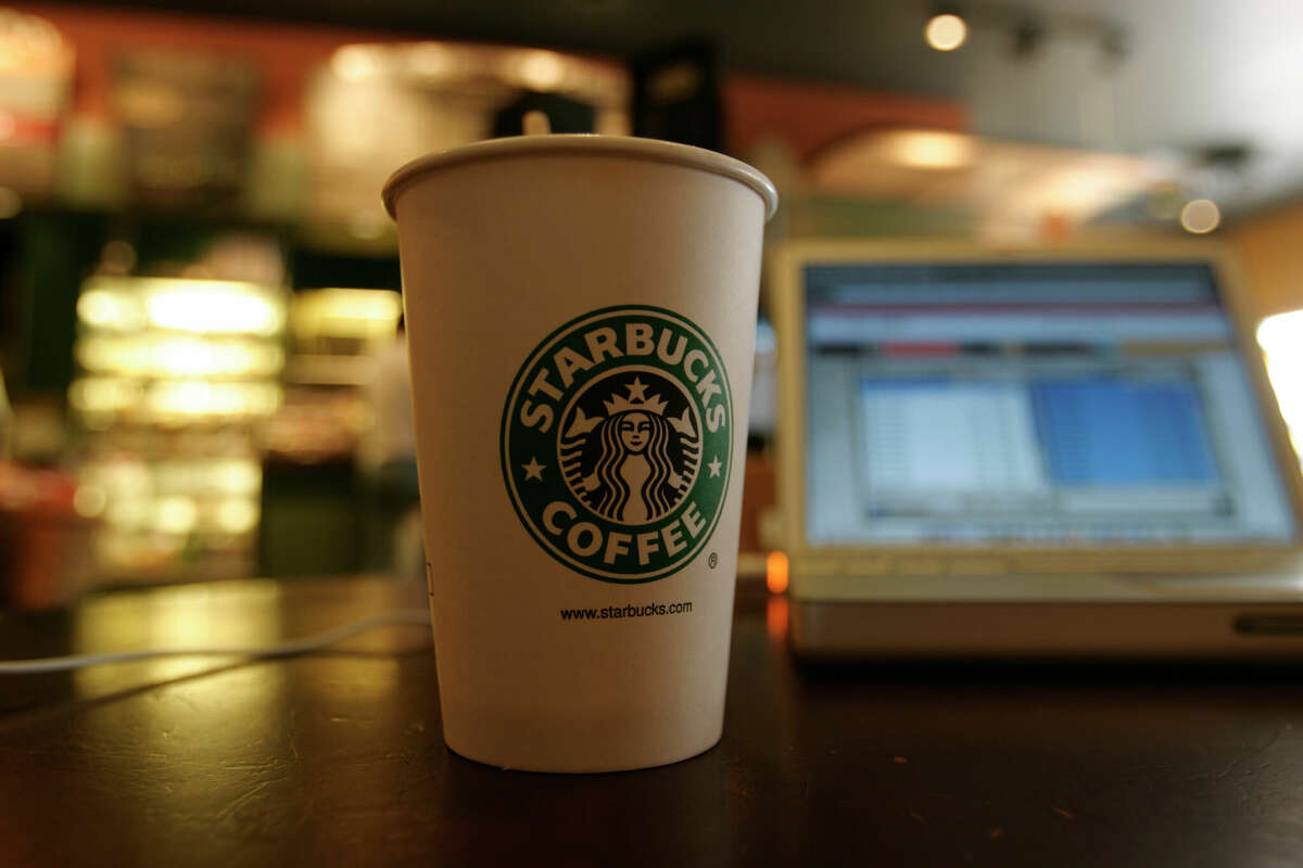 A coffee cup sits next to a laptop connected to the Internet using a Wi-Fi modem at a Starbucks coffee house.