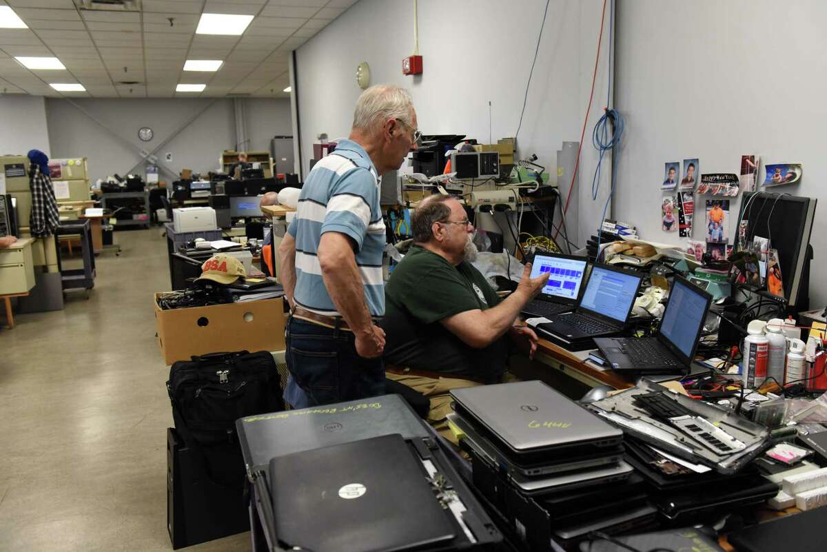 Terry Lustofin, who leads GE Elfun Computer Rehab of Schenectady Inc., left, works with GE retiree and volunteer computer technician, Bernard T. Shaw, right, at the group’s workshop space, which is donated by General Electric on Tuesday, May 24, 2022, at GE in Schenectady, N.Y. The volunteer organization takes broken or old computers, rehabs them and gives them away to schools and non-profits. The organization is looking for more computer donations.