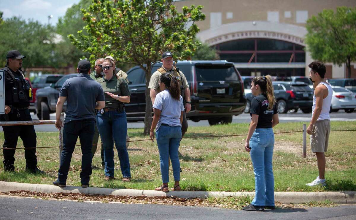 A law enforcement officer tells people Tuesday afternoon, May 24, 2022 that Uvalde High School is secure after a school shooting at the nearby Robb Elementary School in Uvalde, Texas.