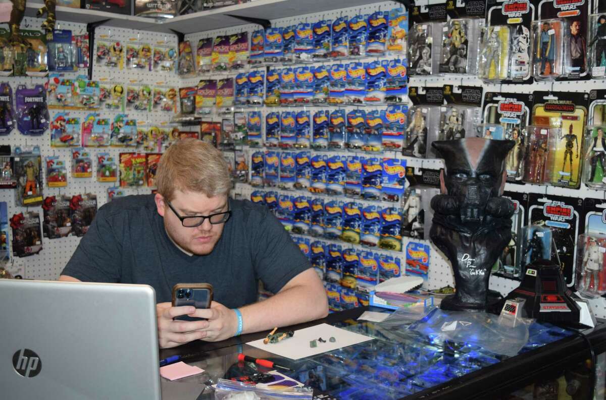 Owner Billy Barrett is flanked by toys of all kinds at Destination Toys, 228A W. Morton Ave., while sitting at the front counter. The store carries collectibles, comics and other items from the 1970s through present-day.