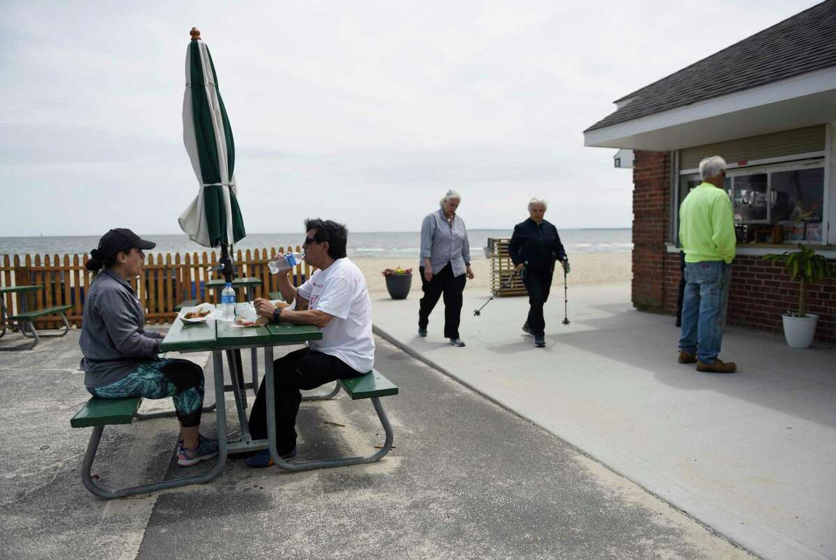 Greenwich residents Adriana and Cesar Alba enjoy a meal at the concession stand on the beach at Greenwich Point Park in Old Greenwich on Tuesday.