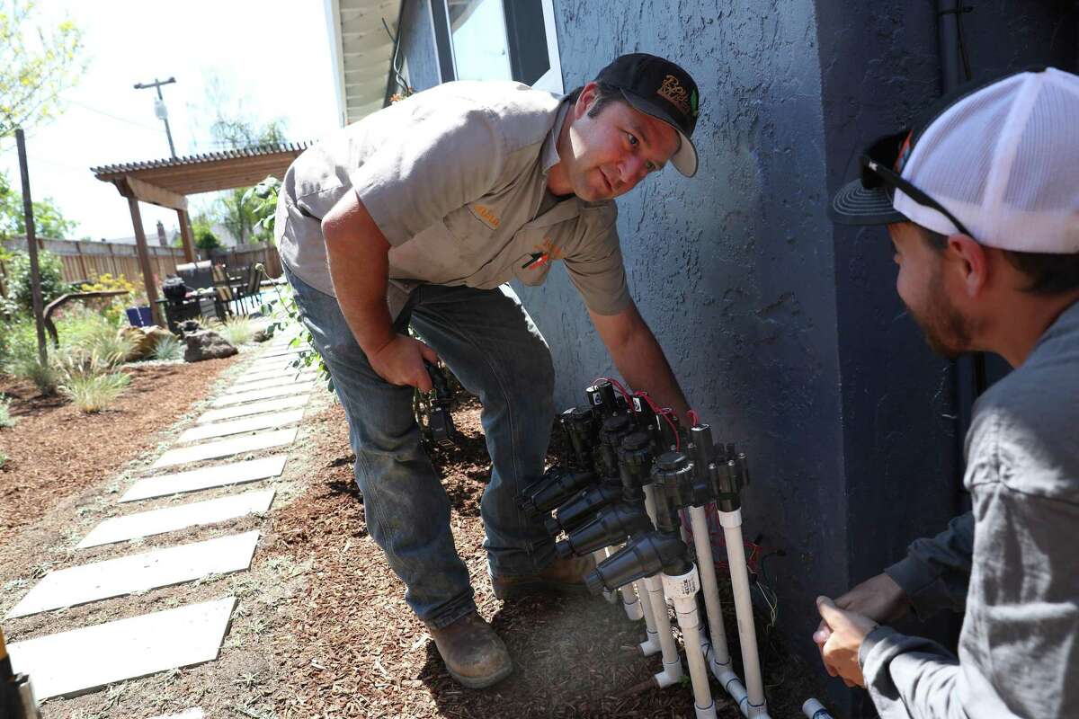 Alan Hackler (left), owner of Bay Maple Wild California Gardens, talks with Mark Adams, a gray-water technician with the company, as they fine-tune the gray-water system recently installed at a home in San Jose. Water-saving landscaping is an urgent priority for California water officials.