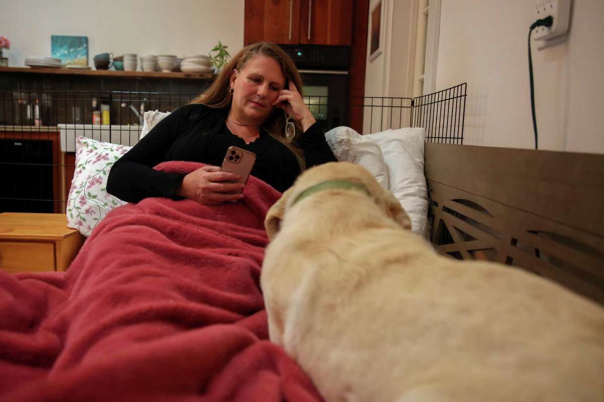 Shelley Hayden of Sonoma relaxes at home with her dog Theo. She suffers from long COVID. A new study identifies seven distinct symptoms as consistent with long COVID.