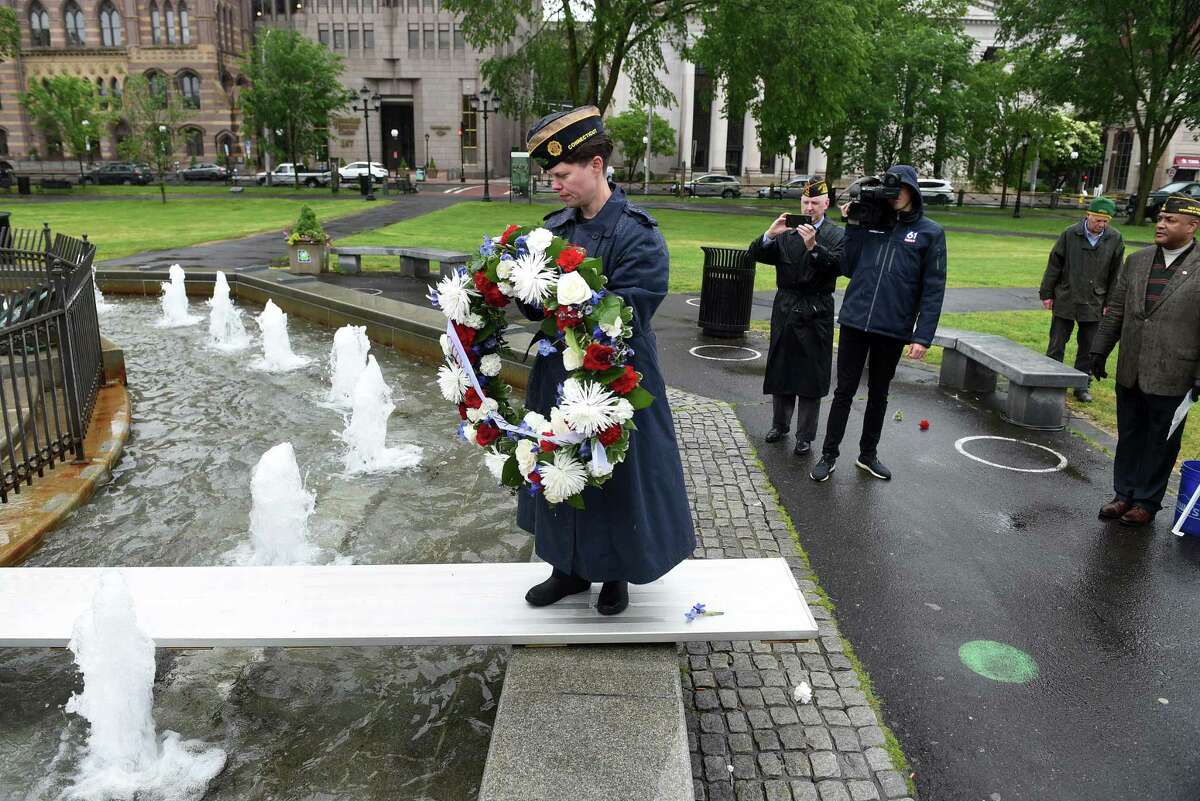 Chaplain of New Haven American Legion Post 210 Britt Conroy carries a wreath across the fountain at the World War I Memorial during a Memorial Day ceremony on the New Haven Green May 30, 2021.