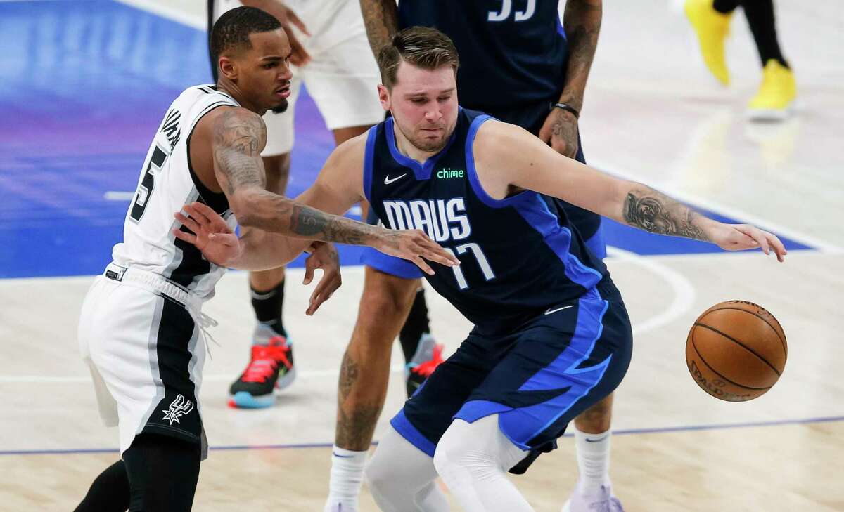 Dallas Mavericks guard Luka Doncic (77) reaches for the ball, while fending off San Antonio Spurs guard Dejounte Murray (5) during the first half of an NBA basketball game Wednesday, March 10, 2021, in Dallas. (AP Photo/Brandon Wade)