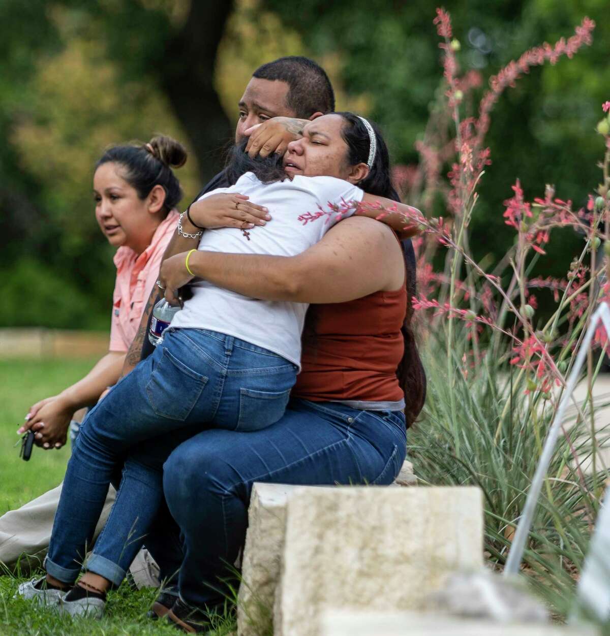 A woman with a rosary in her hand his a child Tuesday, May 24, 2022 outside the Uvalde civic center where parents were being reunited with their children after at least 14 students and 1 teacher were killed when a gunman opened fire at Robb Elementary School in Uvalde.