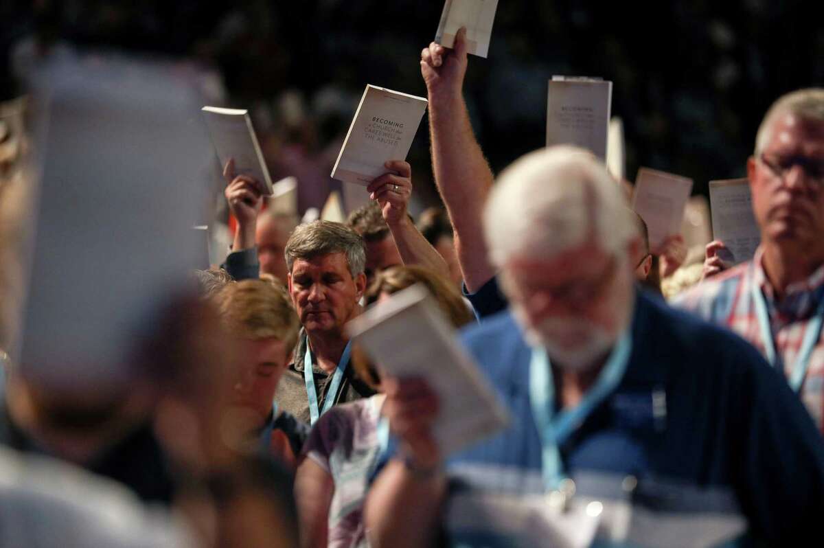 Bill Golden, and thousands of others, hold up copies of a training handbook related to sexual abuse within Southern Baptist churches during a speech by SBC President J. D. Greear on the second day of the SBC's annual meeting June 12, 2019, in Birmingham.