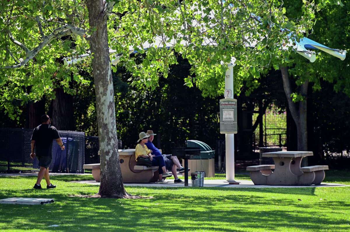 A couple gets a little shade in the picnic area at Heather Farms in Walnut Creek on Tuesday. Contra Costa County cities may see the most heat this week.