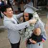 Christian Cantu, left, puts a lei made of dollar bills around the neck of his sister, Stormy, before a graduation ceremony at Cynthia Woods Mitchell Pavilion, Tuesday, May 24, 2022, in The Woodlands.