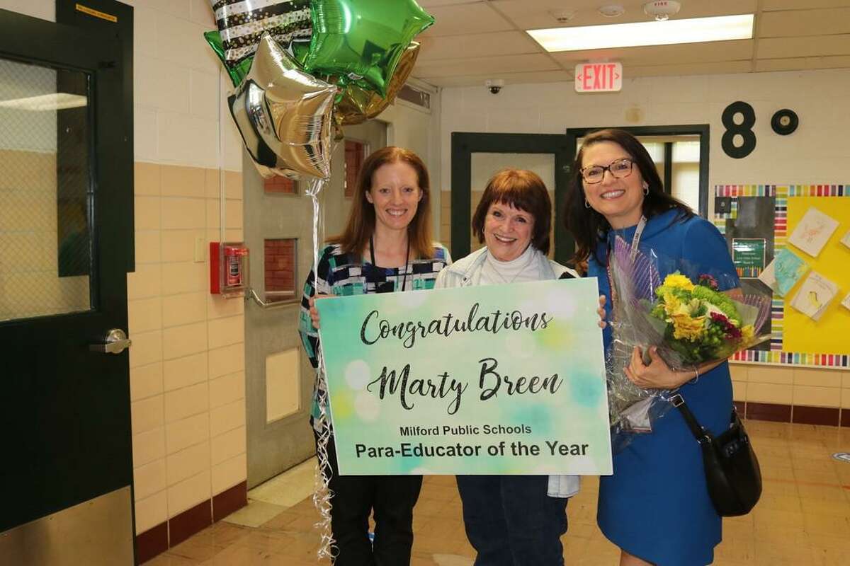 Marty Breen, this year’s Para-Educator of the Year for the Milford Public Schools, is surprised by Live Oaks Elementary teacher leader Darlene Koosa, left, and Superintendent Anna Cutaia.