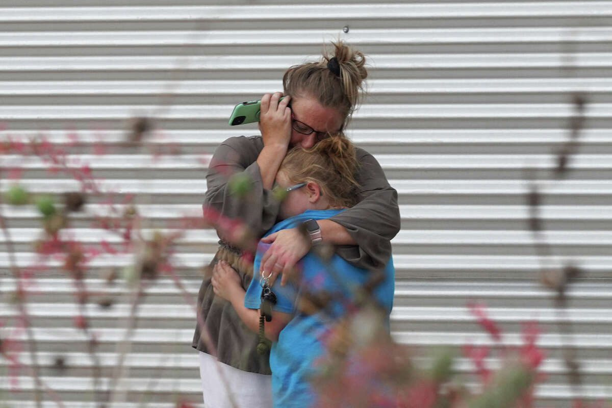 TOPSHOT - A woman cries and hugs a young girl while on the phone outside the Willie de Leon Civic Center where grief counseling will be offered in Uvalde, Texas, on May 24, 2022. - A teenage gunman killed 18 young children in a shooting at an elementary school in Texas on Tuesday, in the deadliest US school shooting in years. The attack in Uvalde, Texas -- a small community about an hour from the Mexican border -- is the latest in a spree of deadly shootings in America, where horror at the cycle of gun violence has failed to spur action to end it. (Photo by allison dinner / AFP) (Photo by ALLISON DINNER/AFP via Getty Images)