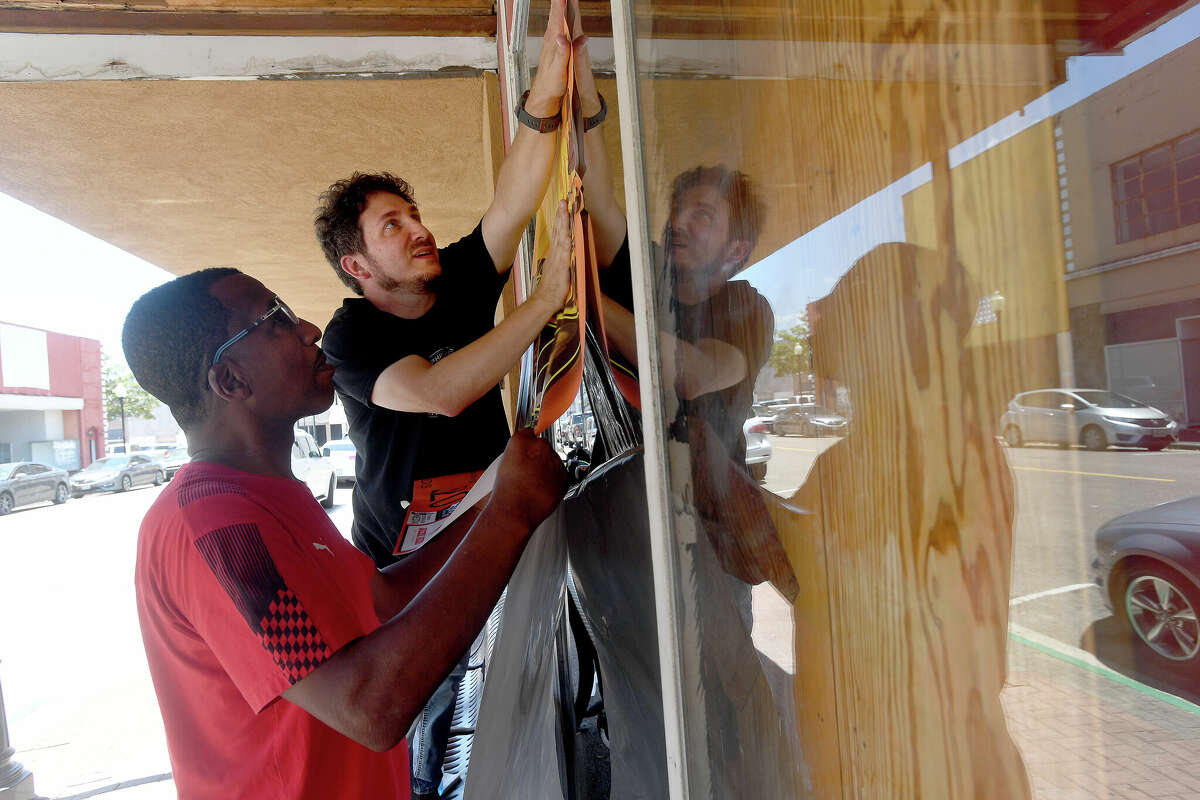 Comedy club producers All Freeman and Steven Kay prepare the windows to put up signage advertising the show at Jazz & Jokes on Orleans Street, which will reopen Memorial Day weekend as the SpeakEasy Comedy Lounge at Jazz & Jokes. Photo made Thursday, May 19, 2022. Kim Brent/The Enterprise