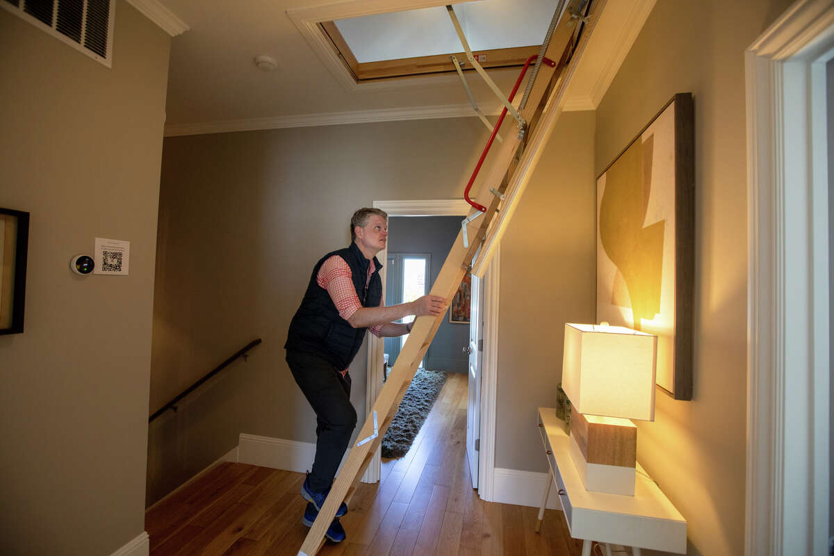 SFGATE columnist Drew Magary climbs a ladder to view an attic space at 231 12th Ave., a house for sale in San Francisco on May 24, 2022. He is inspecting the state of the real estate market in San Francisco.