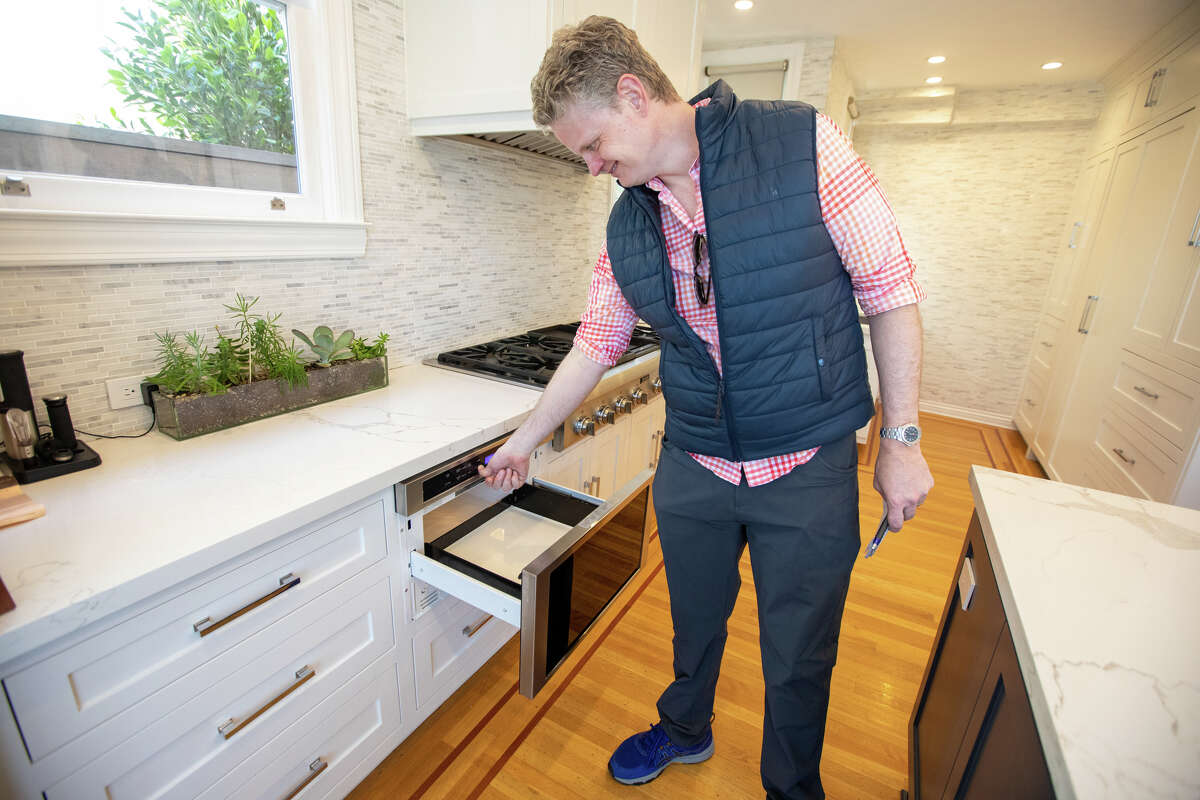 SFGATE columnist Drew Magary checks out an undercounter microwave at 2200 Lyon St., a house for sale in San Francisco on May 24, 2022. He is inspecting the state of the real estate market in San Francisco.