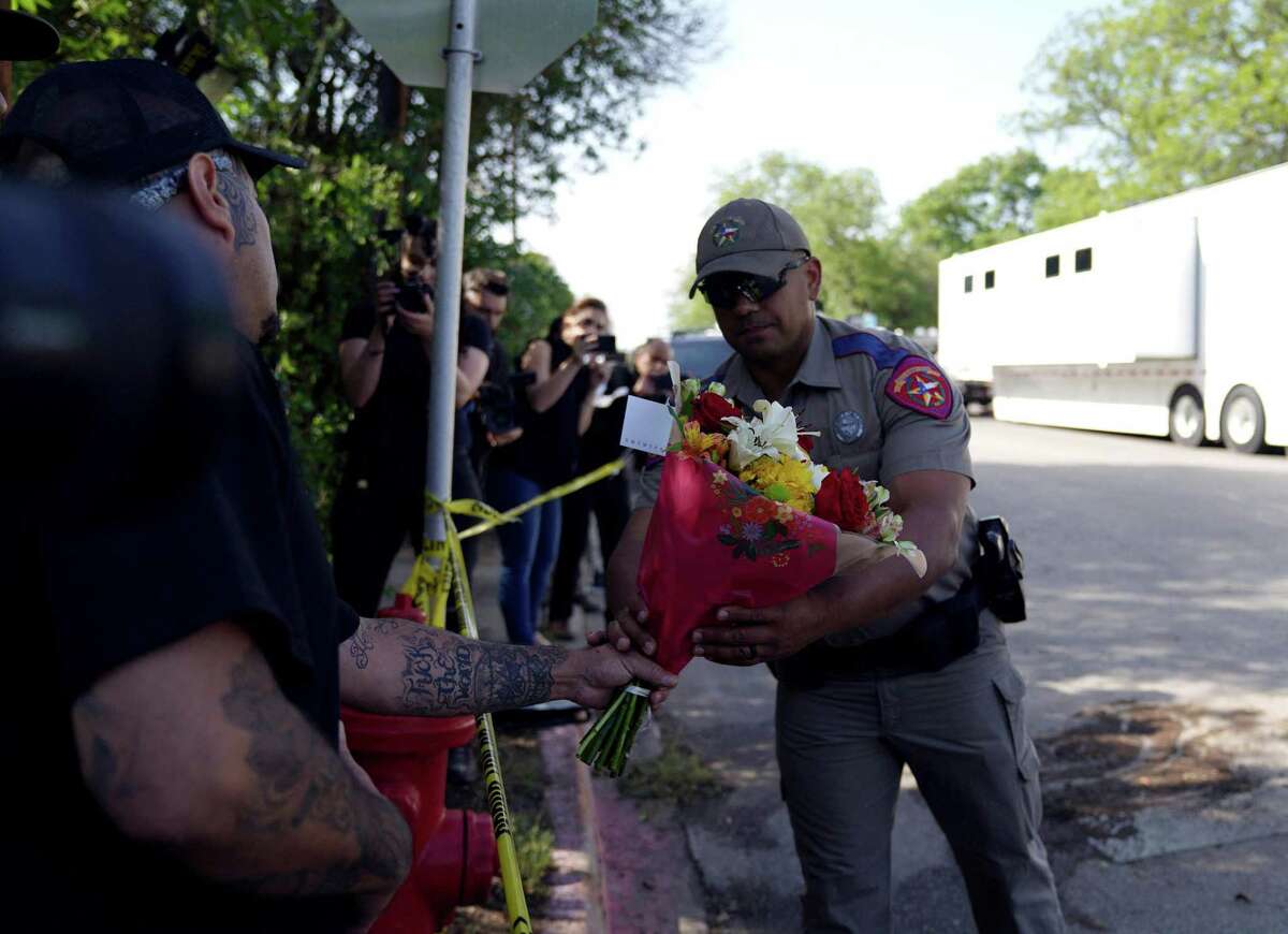 A police officer takes flowers from a resident to be placed at a makeshift memorial outside Robb Elementary School in Uvalde, Texas, May 25, 2022.