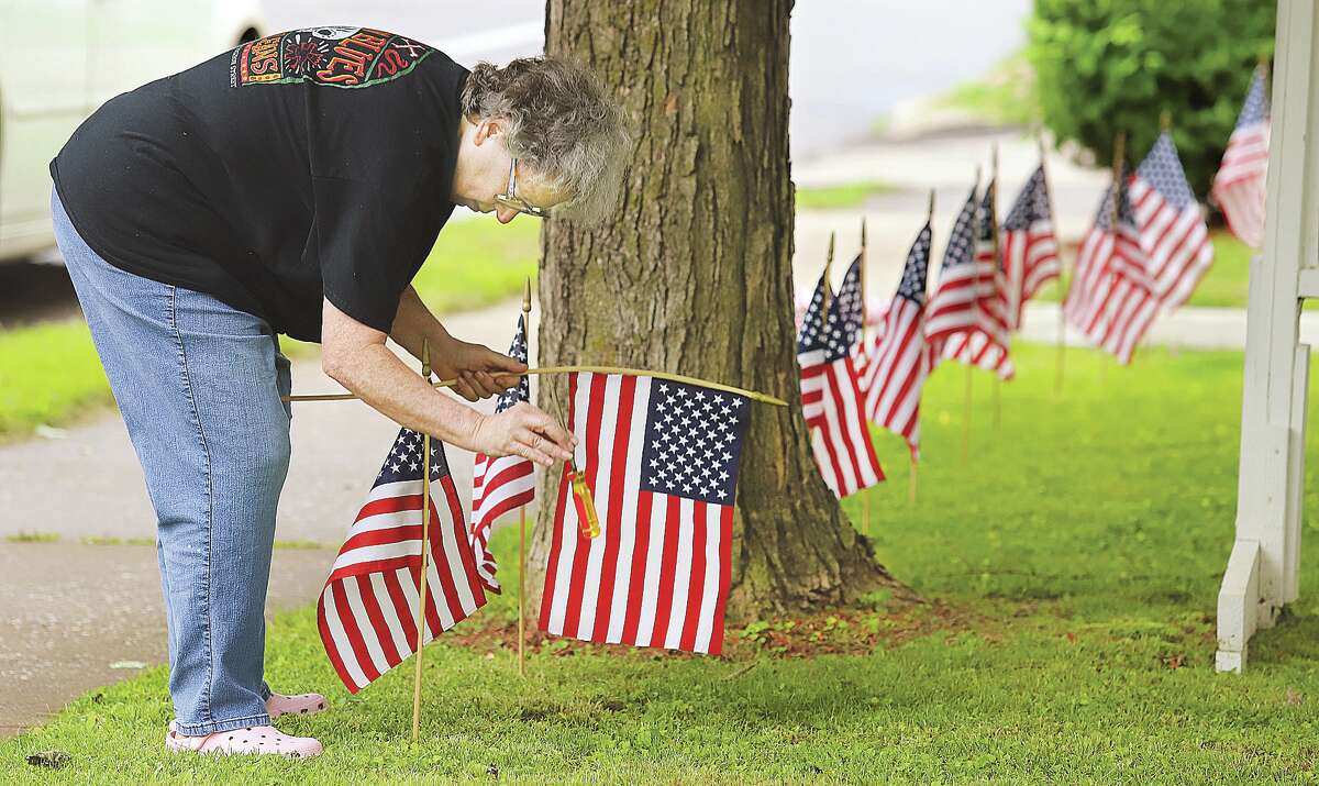 John Badman|The Telegraph Jan Christopher, property manager for the Town House Apartments on Washington Avenue in Alton, placed small American flags on the front lawn of the apartment complex Wednesday ahead of the upcoming Memorial Day Weekend.