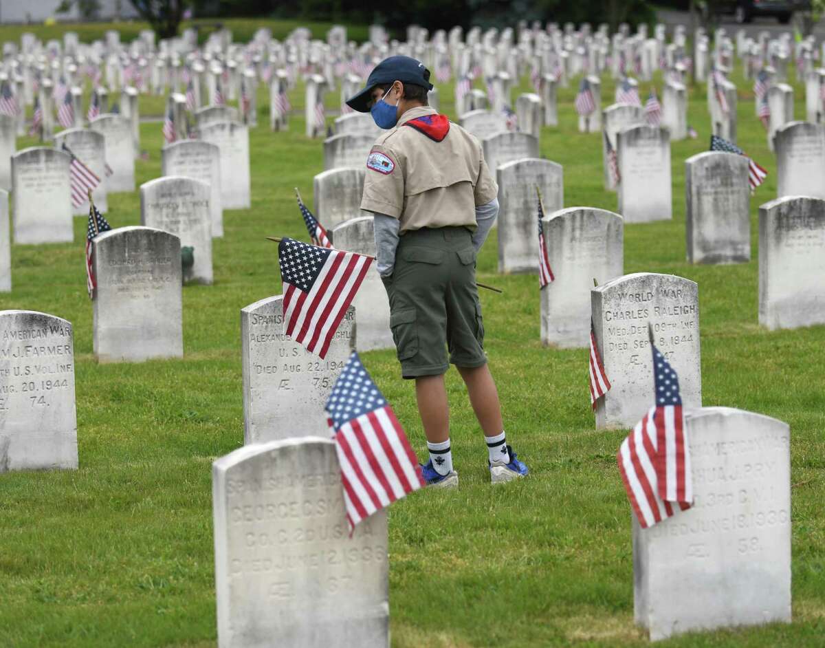 Jackson Lucas, 12, of Boy Scout Troop 35, looks at the flags placed on veterans' graves during the Memorial Day Ceremony at the State of Connecticut Veterans' Cemetery in Darien, Conn. Monday, May 31, 2021. The parade and ceremony honored veterans who gave their lives in service to the country.
