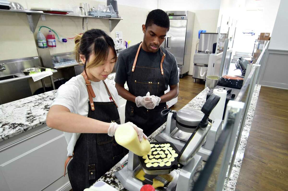 Sabrina Yang makes bubble waffles as employee Monty Barnes looks on at Shiro Desserts and Drinks on Bedford Street in Stamford, Conn., on Tuesday May 24, 2022. Shiro, which offers Asian-inspired desserts and tea drinks, was opend last week by Yang, a student at UConn Stamford majoring in business management.