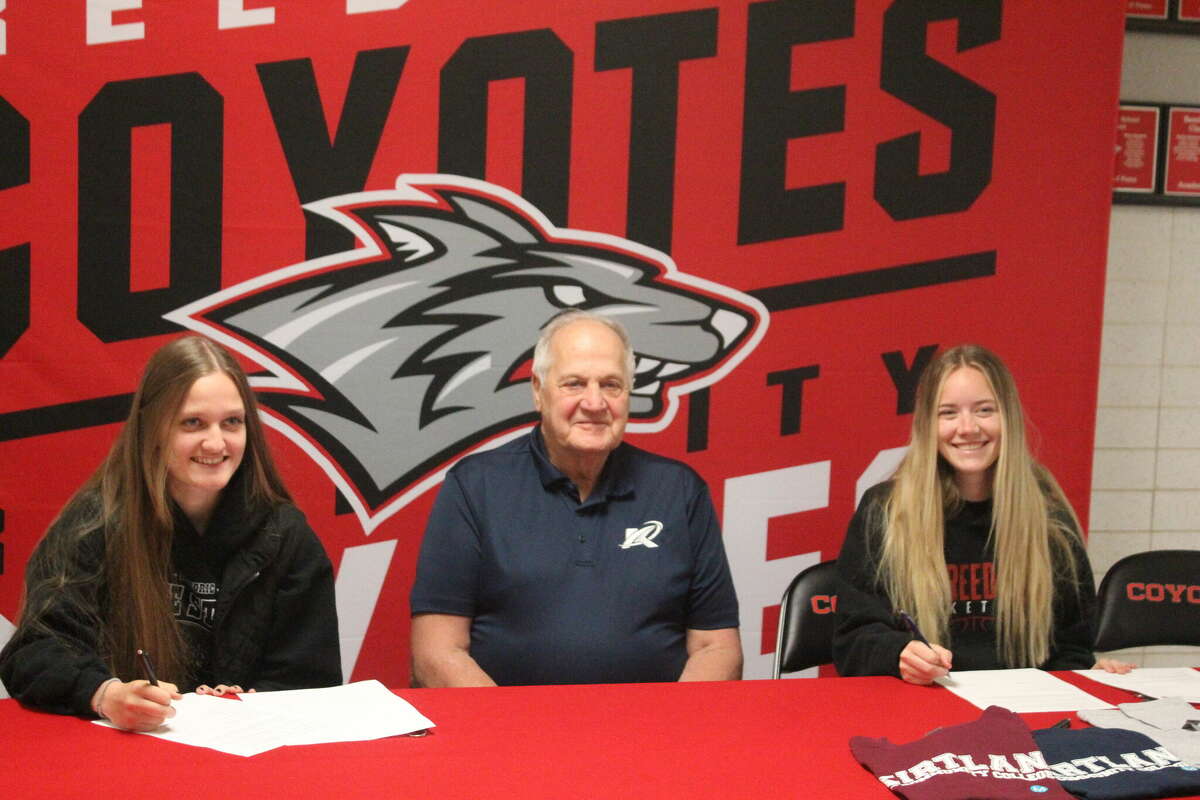 Kirtland coach Tom Ritter (center) signs Racquel DuBreuil (left) and Paige Lofquist on Wednesday.