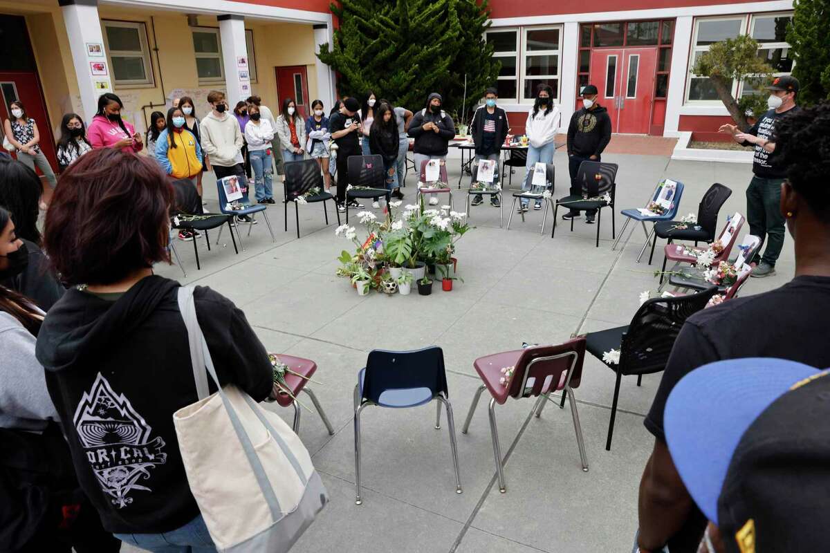 Peer resources teacher Morgan Wallace (top right) speaks to Abraham Lincoln High School students as they gather at a memorial for the victims of the school shooting in Texas.