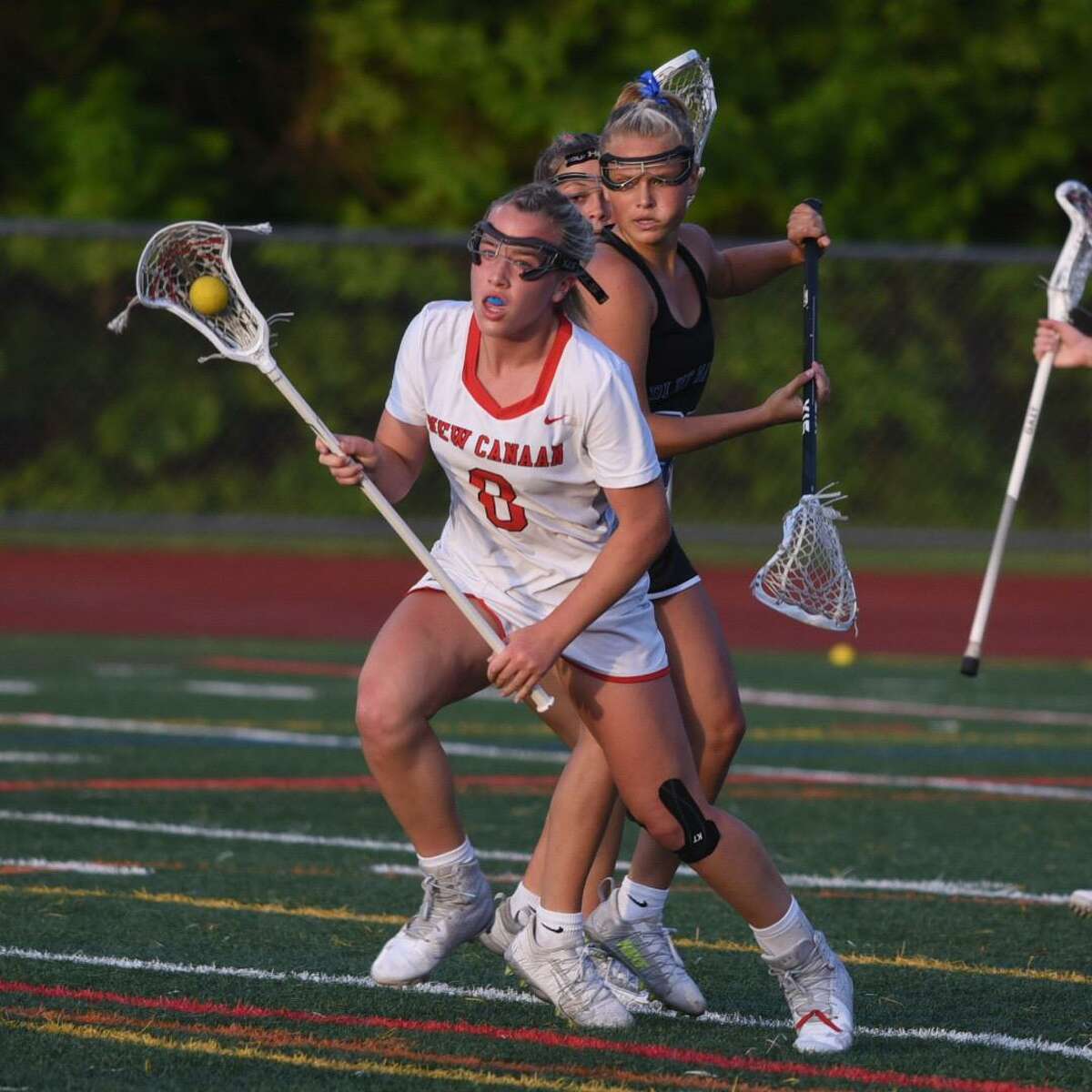 New Canaan’s Devon Russell carries the ball in front of Darien’s Molly McGuckin during the FCIAC girls lacrosse championship on Wednesday in Norwalk. For a full recap, go to CTInsider.com/sports.