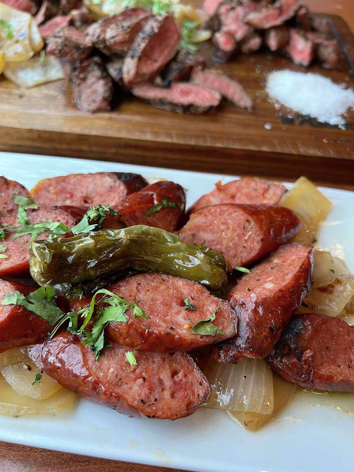 Wagyu sausage is grilled and served with grilled onions at Tu Asador, a Mexican-style steakhouse in Castle Hills.