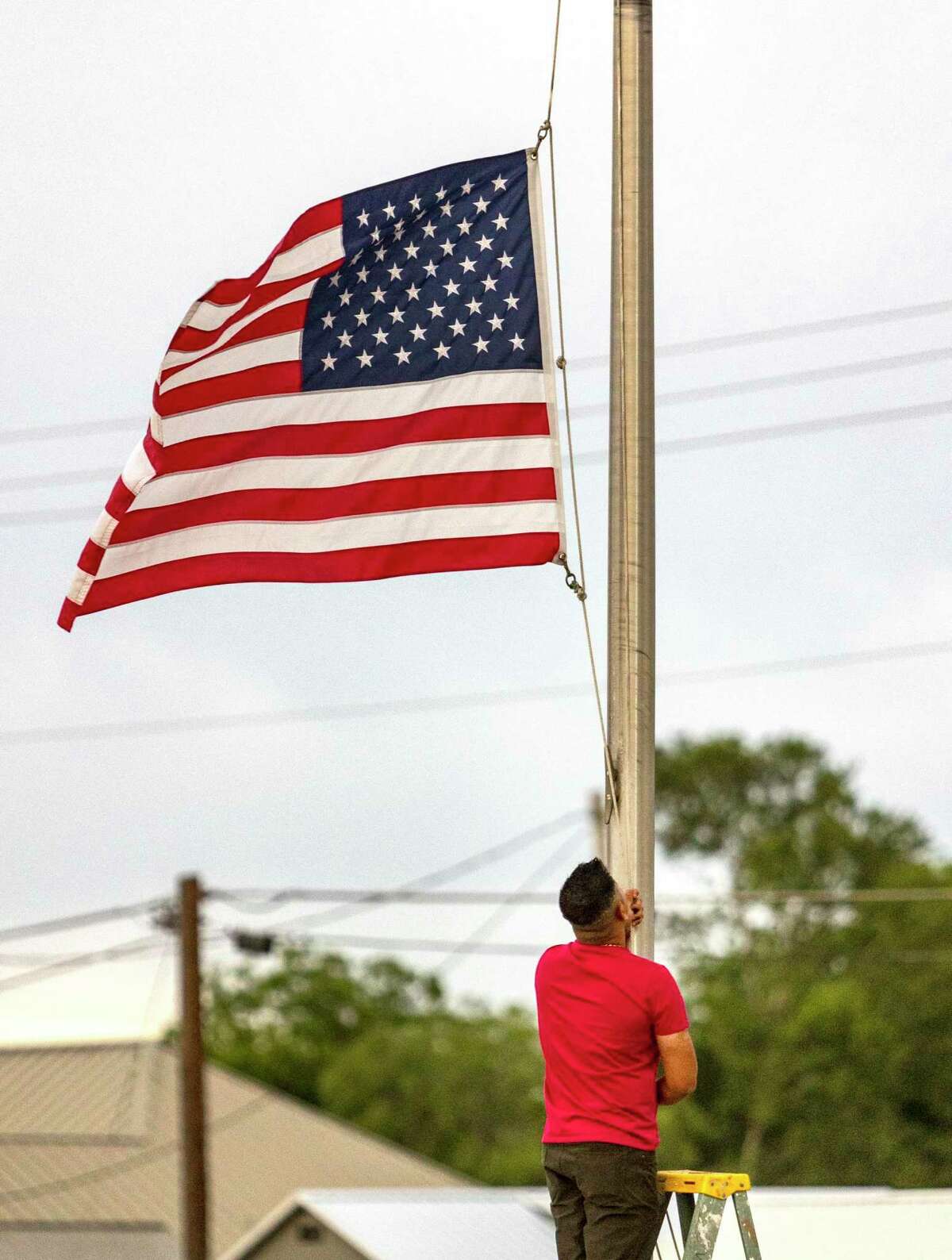 Janish Patel lowers the flag to half staff Tuesday, following the massacre at Robb Elementary School.
