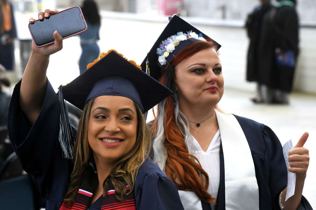 Graduates wave and pose for family members while entering Commencement for the Housatonic Community College Class of 2022, held at the Hartford Healthcare Amphitheater in Bridgeport, Conn. May 26, 2022.