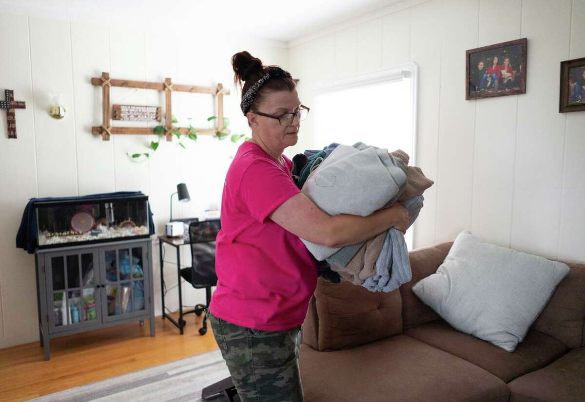 Carie Mathis, who is trying to pay rent as the Economic Development Department fixes benefit problems, carries laundry in the Crockett home she rents.