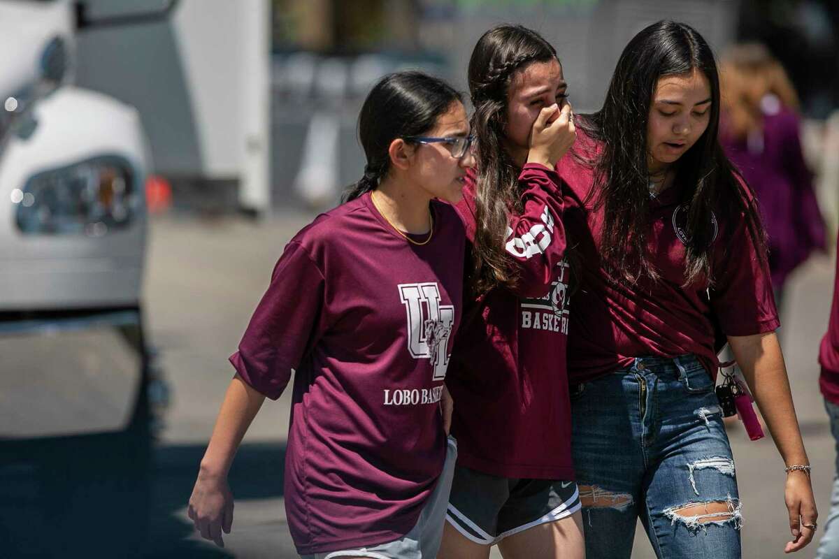 Young people comfort each other after leaving a memorial at Robb Elementary School in Uvalde. On Tuesday, an 18-year-old gunman entered the school and killed at least 19 students and two educators.