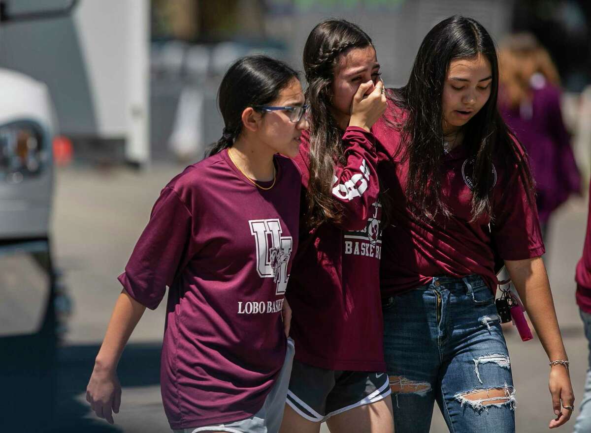 Overcome with emotion, young people comfort one another after leaving a memorial created outside Robb Elementary School in Uvalde for the massacre victims.