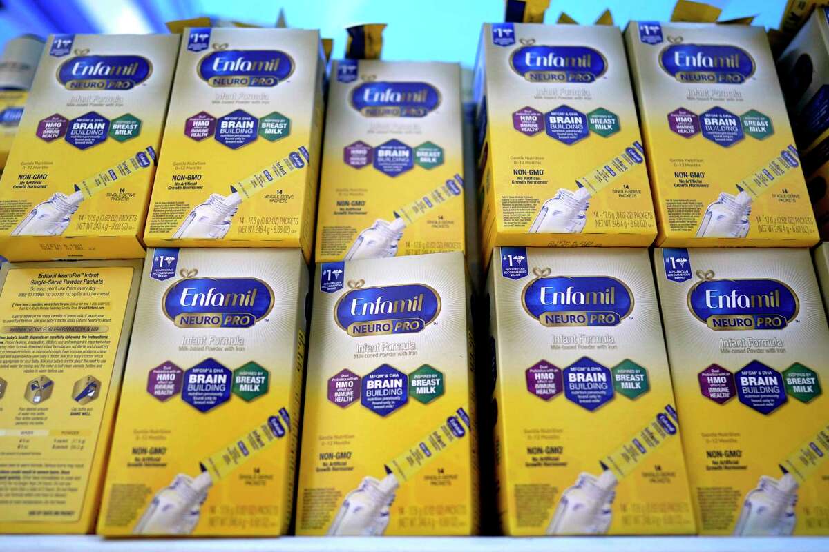 Infant formula is stacked on a table in Houston during a baby formula drive to help with the shortage. President Joe Biden has invoked the Defense Production Act to speed production of infant formula and has authorized flights to import supply from overseas.