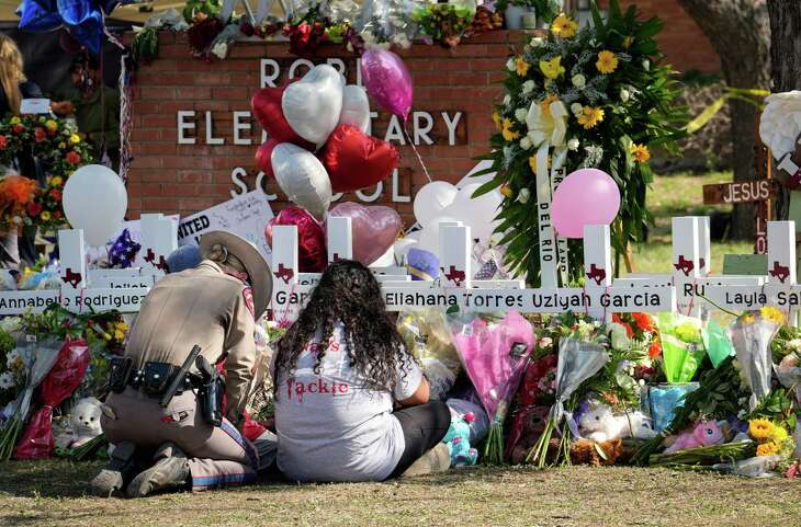 A Texas DPS trooper comforts a woman as she and a young boy grieve Thursday, May 26, 2022, at Robb Elementary School in Uvalde.
