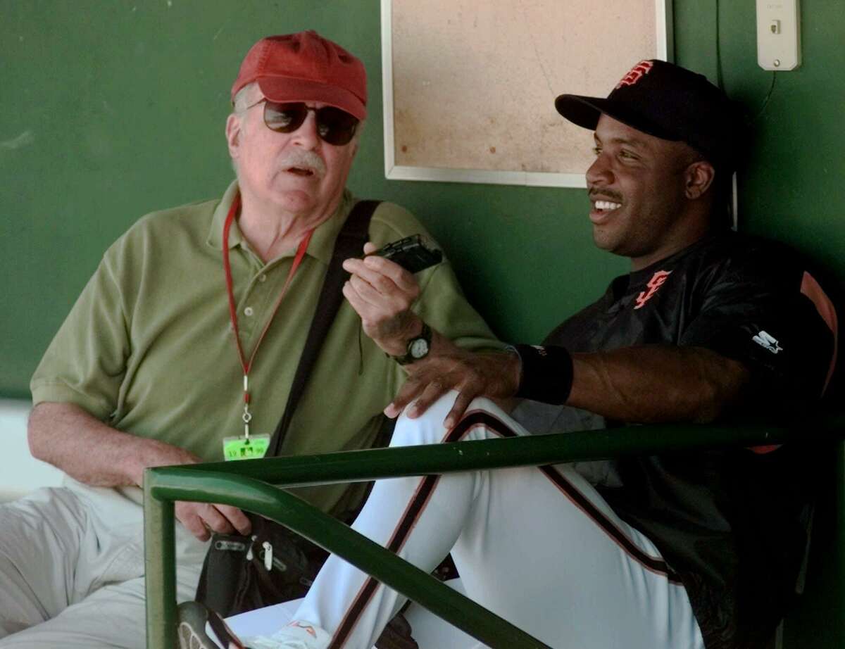 San Francisco Giants' Barry Bonds, right, sits in the dugout for an interview with baseball author Roger Angell, left, prior to the Giants spring training game against the Chicago White Sox in Scottsdale, Ariz., Tuesday March 23, 1999.(AP Photo/Eric Risberg)