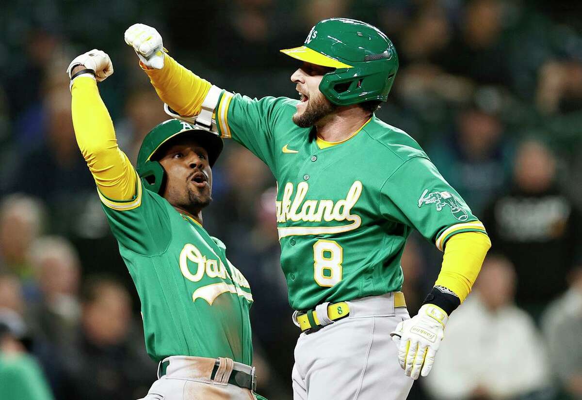 Jed Lowrie (8), the only switch hitter on the A’s active roster, celebrates with Tony Kemp after hitting a two-run home run during the fifth inning against the Mariners at T-Mobile Park in Seattle on Tuesday.