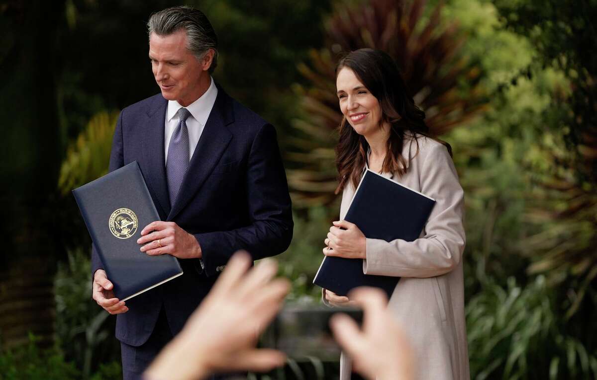 California Gov. Gavin Newsom and New Zealand Prime Minister Jacinda Ardern hold copies of agreements they made at the San Francisco Botanical Garden.