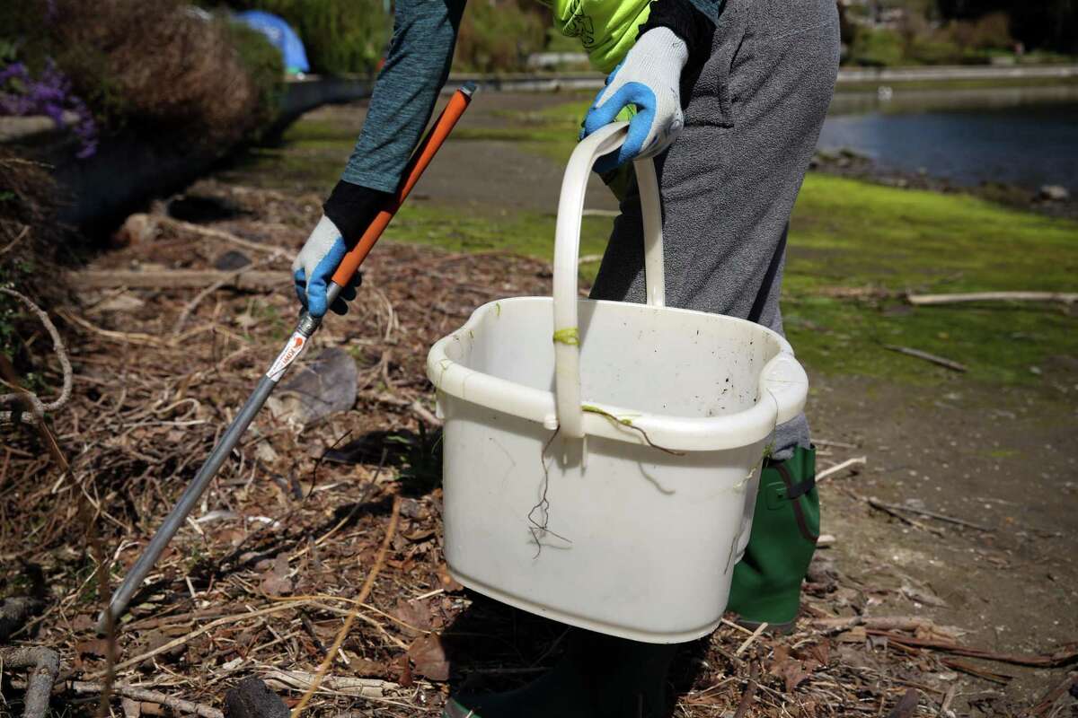 Kathy Branddenburg uses tongs to pick up small pieces of trash at Lake Merritt in Oakland, Calif. on Tuesday, April 5, 2022.