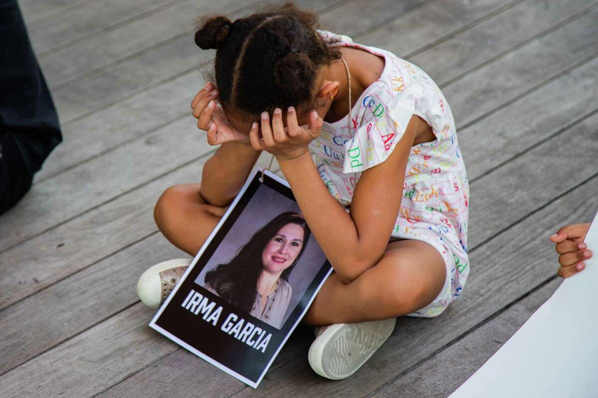 A child at Discovery Green has a photo of Irma Garcia, who taught for 23 years at Robb Elementary School. Garcia was one of two teachers killed at the school mass shooting in Uvalde. 