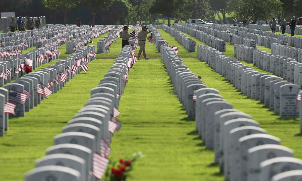 Boy Scouts walk along rows of headstones with flagsat Fort Sam Houston National Cemetery in 2019. This Memorial Day, throughout the country, Americans will raise their flags, honor our soldiers and visit their gravesites.
