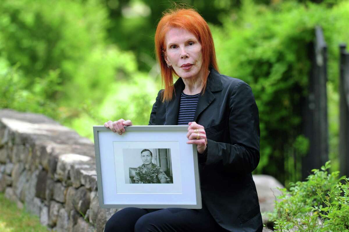 Eilhys England Hackworth, who started a nonprofit to help veterans cope with traumatic brain injuries and PTSD, poses with a photo of her late husband, Col. David H. Hackworth, at her home in Greenwich, Conn., on Thursday May 26, 2022.