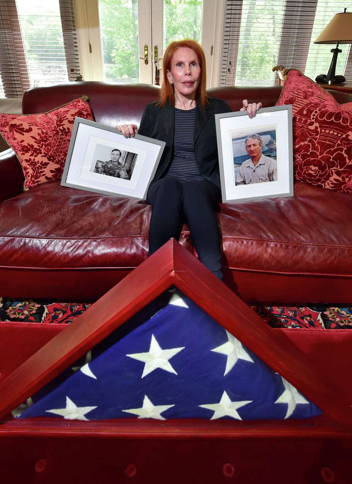 Eilhys England Hackworth, who started a nonprofit to help veterans cope with traumatic brain injury and PTSD, poses with photos of her late husband, Col. David H. Hackworth, at her home in Greenwich, Conn., on Thursday May 26, 2022.