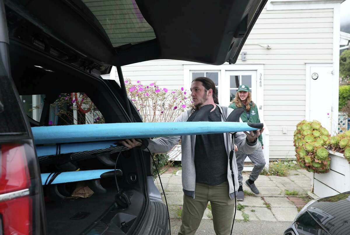 Ben Howard (left) loads rented surfboards into a vehicle as his brother Nick Howard watches. The brothers were vacationing with family, all from Nebraska, in a short-term rental at Stinson Beach.